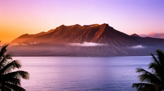 Vue panoramique de La Réunion au lever du soleil avec montagnes en arrière-plan et océan au premier plan